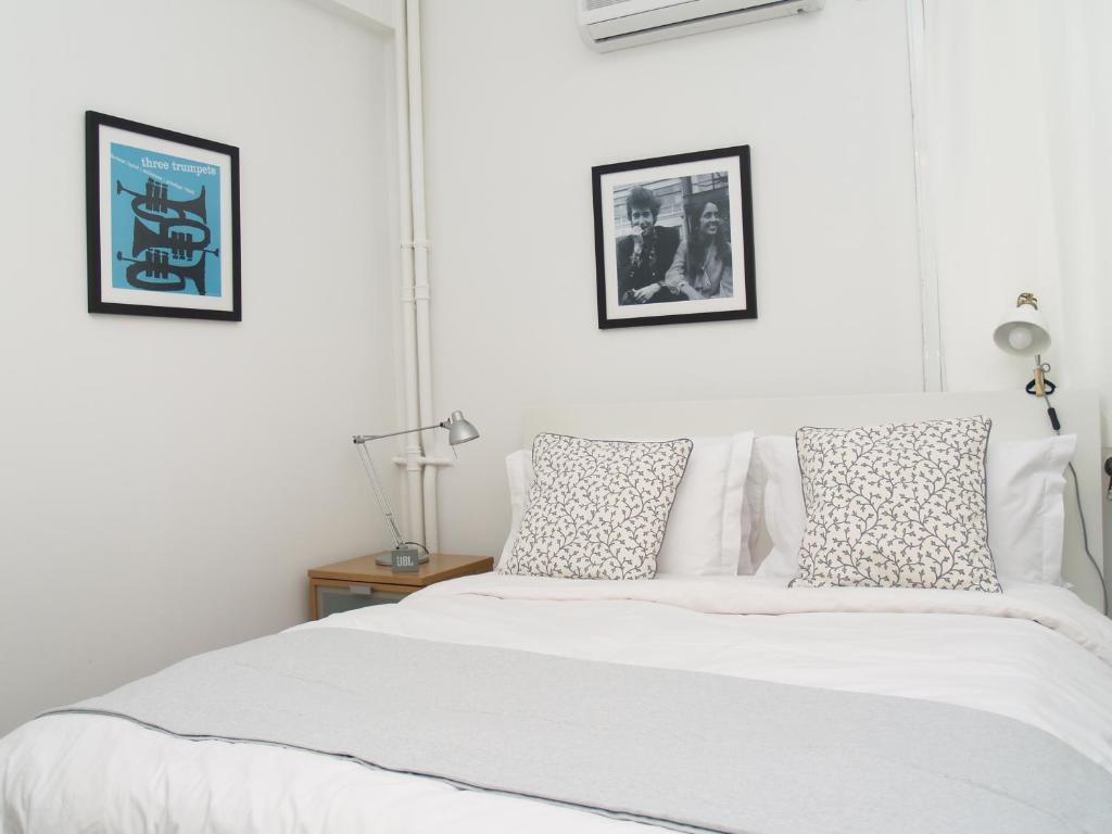 a white bedroom with a white bed with pillows at Artistic Deco Apartment in Athens