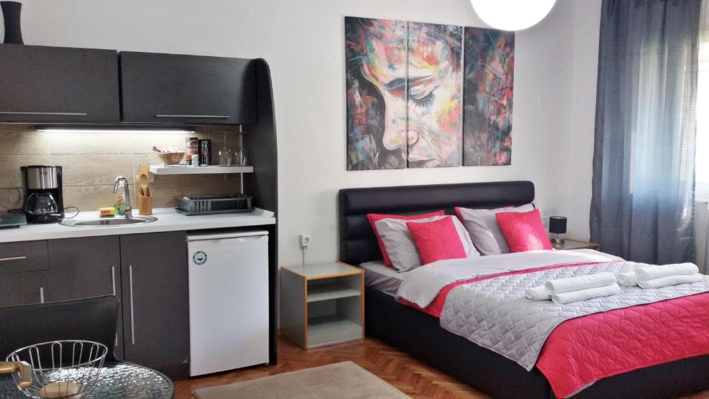 Un dormitorio con una cama con almohadas rojas y una pintura en The House Apartments & Guest Rooms, en Ohrid