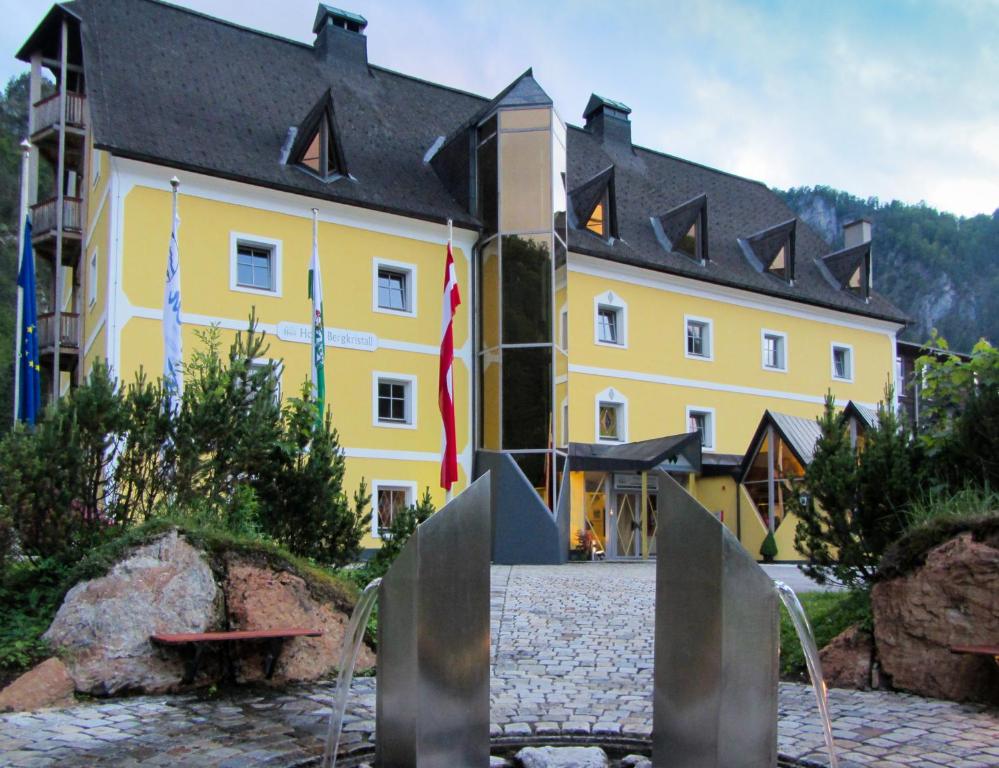 ein gelbes Gebäude mit einer Flagge davor in der Unterkunft Hotel Bergkristall in Wildalpen
