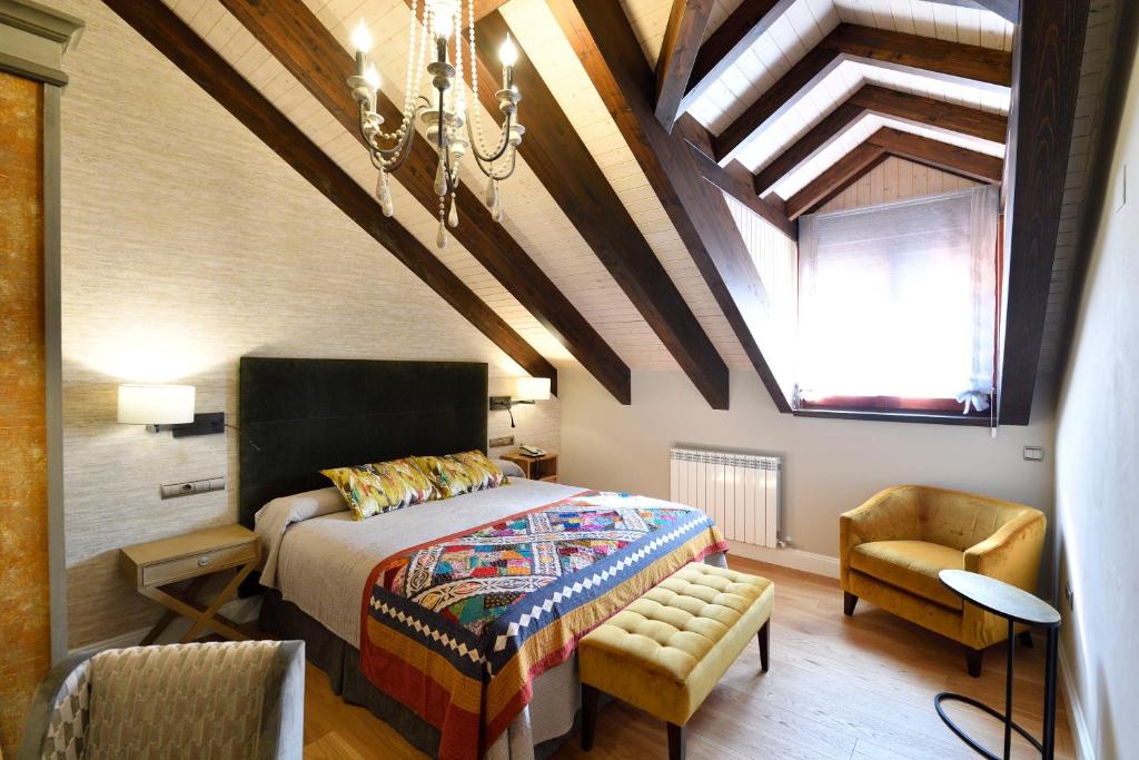 een slaapkamer met een bed, een stoel en een plafond bij Hotel Bujaruelo in Torla