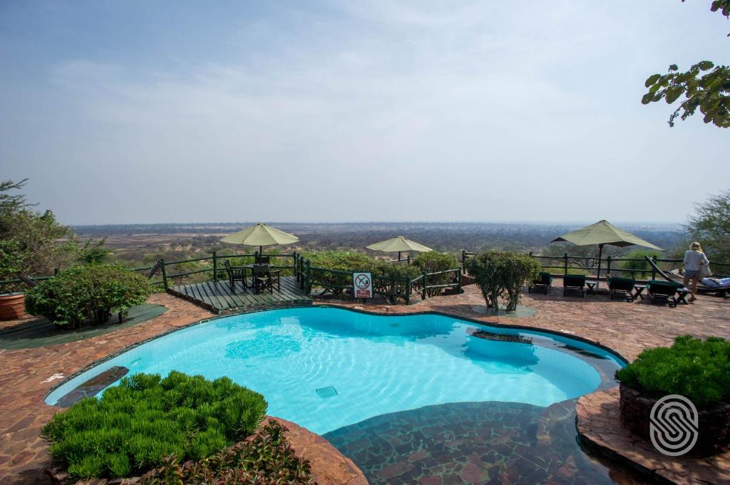 a large swimming pool with a view of the mountains at Kirawira Serena Camp in Handajega