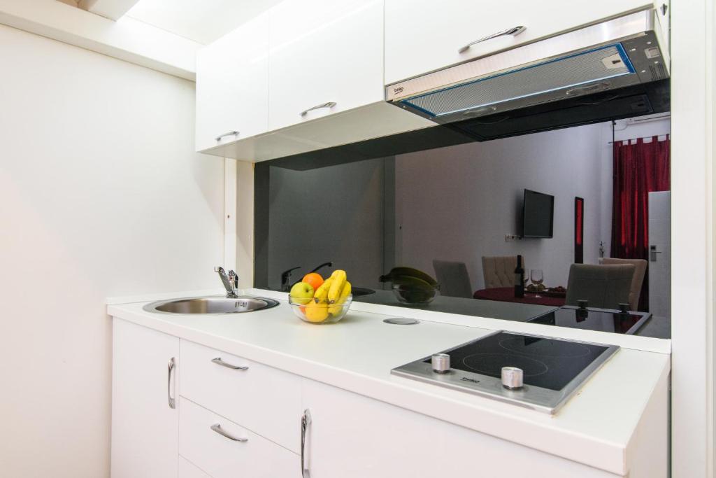 una cucina con lavandino e un cesto di frutta su un bancone di Studio Apartman REA a Trogir