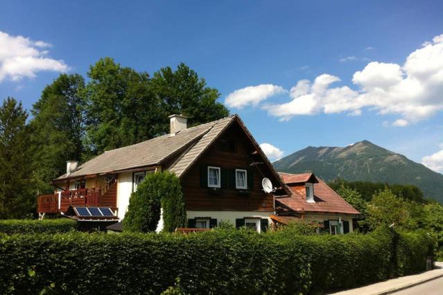 a large wooden house with mountains in the background at Haus Tulpe in Strobl