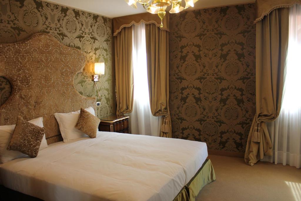 a bedroom with a large bed and a large window at Hotel Casanova in Venice