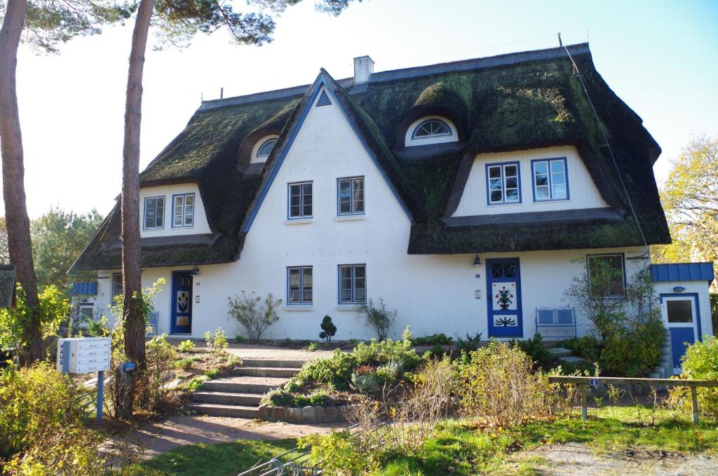 uma casa branca com telhado de palha em FeWo Sonnenblume Achtern Diek em Zingst