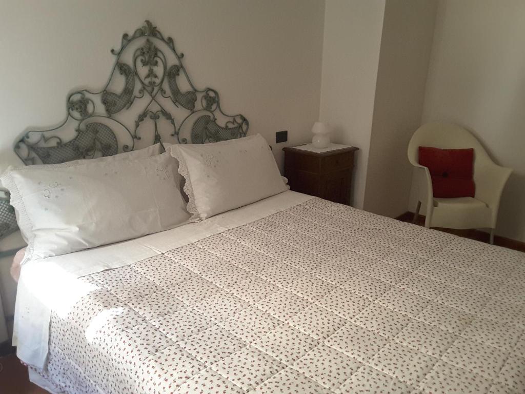 een slaapkamer met een groot wit bed en een rode stoel bij Casa Belfiore Da Andrea in Ferrara