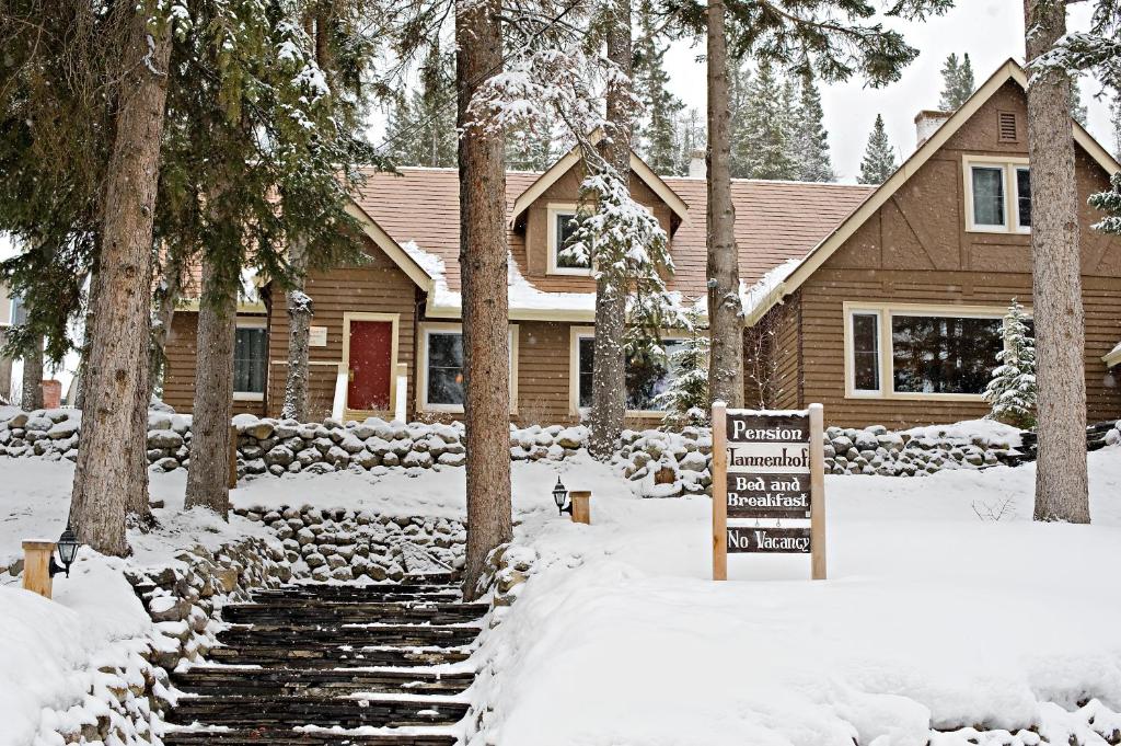 a house in the snow with a sign in front at Banff Boutique Inn - Adults only in Banff