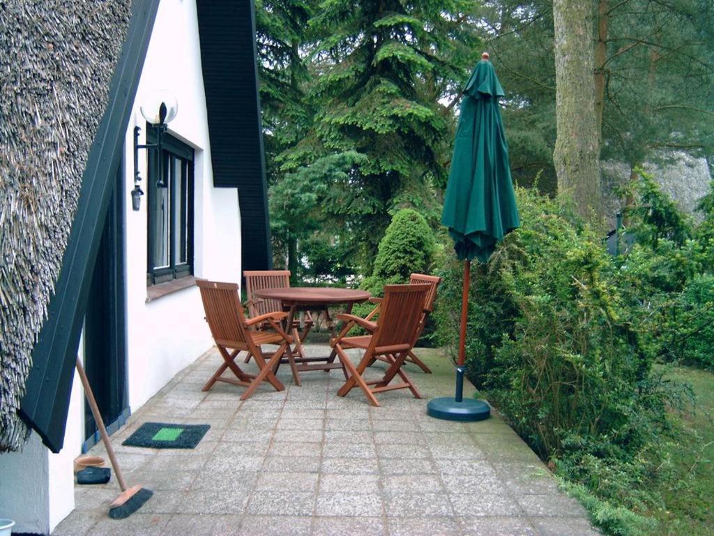 patio con tavolo, sedie e ombrellone di Reetdach-Ferienhaus in Quilitz a Rankwitz