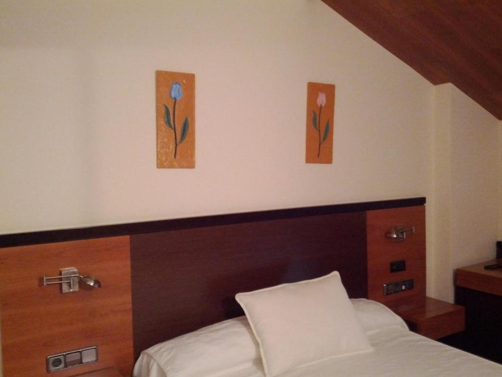 a bedroom with a bed with three paintings on the wall at Doade in Hio