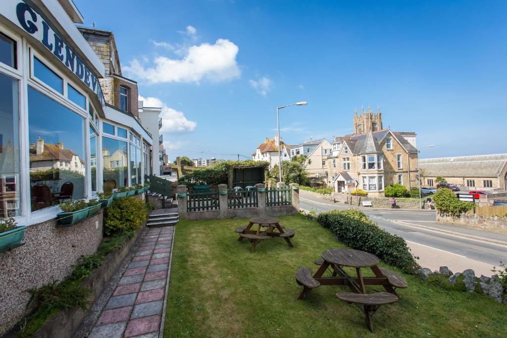 a picnic table and benches on the grass next to a building at The Glendeveor in Newquay