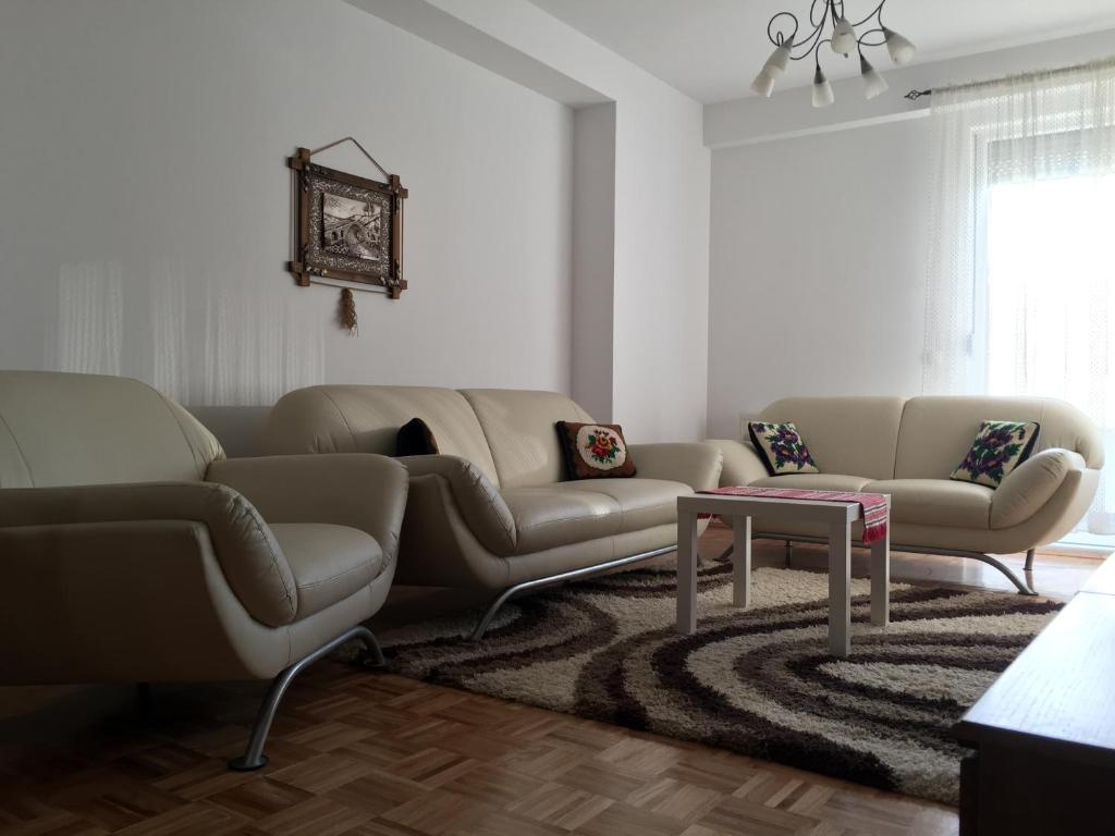 een woonkamer met een bank, 2 banken en een tafel bij Apartment Gashi in Pristina