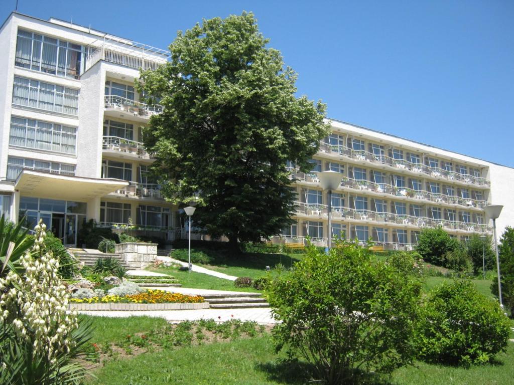 a large building with a tree in front of it at Neptune Hotel in Saints Constantine and Helena