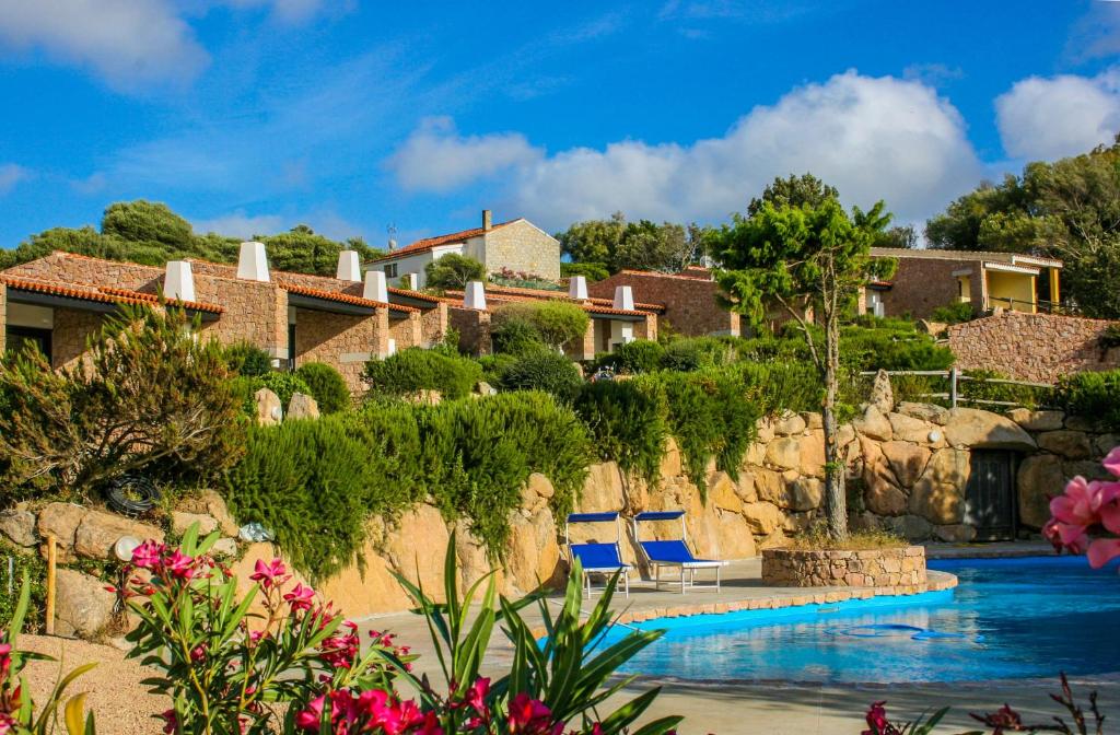 un resort con piscina con due sedie blu di Rena Village a Rena Majore