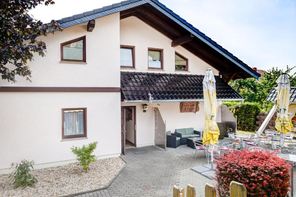 ein Haus mit einer Terrasse mit Stühlen und Sonnenschirmen in der Unterkunft Cafe Hoyer Pension und Appartements in Rödigsdorf