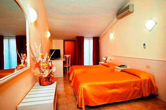 pokój hotelowy z 2 łóżkami z pomarańczową pościelą w obiekcie Hotel Massimino w mieście Anguillara Sabazia