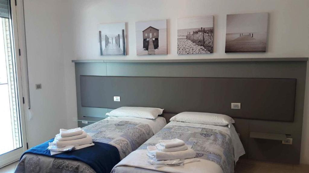 2 Betten in einem Zimmer mit Bildern an der Wand in der Unterkunft B&B La Regina di Rimini in Rimini