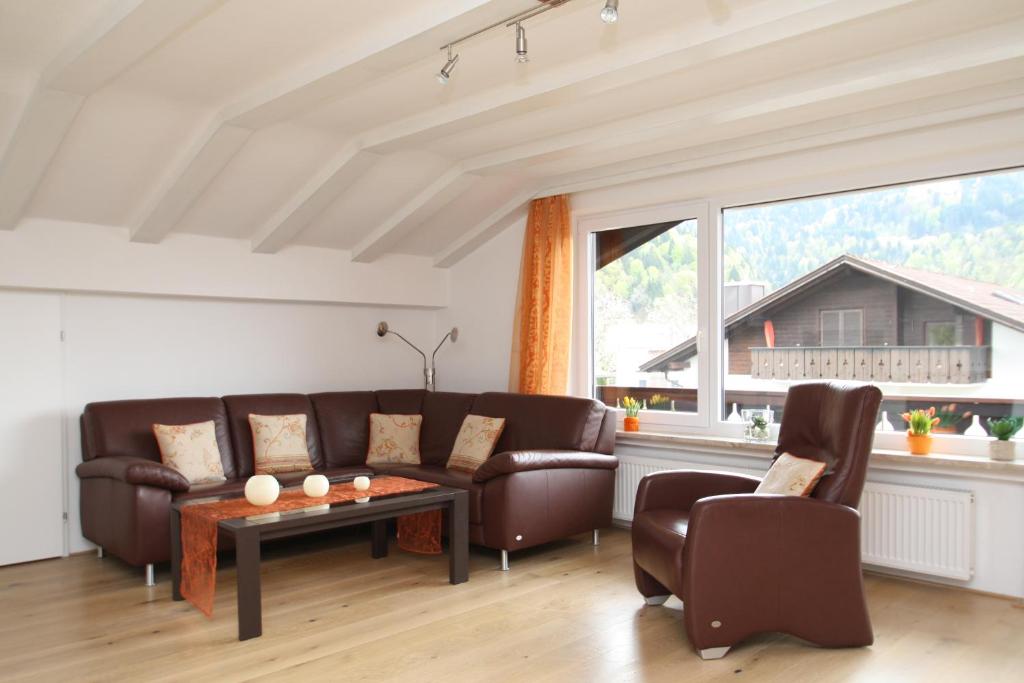 a living room with brown leather furniture and a large window at Apartment Spitzenblick in Garmisch-Partenkirchen