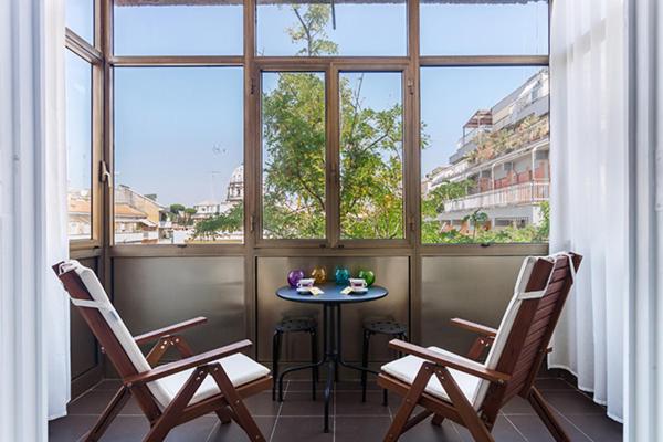 un balcone con 2 sedie, un tavolo e 2 finestre di St Peter Lodge a Roma