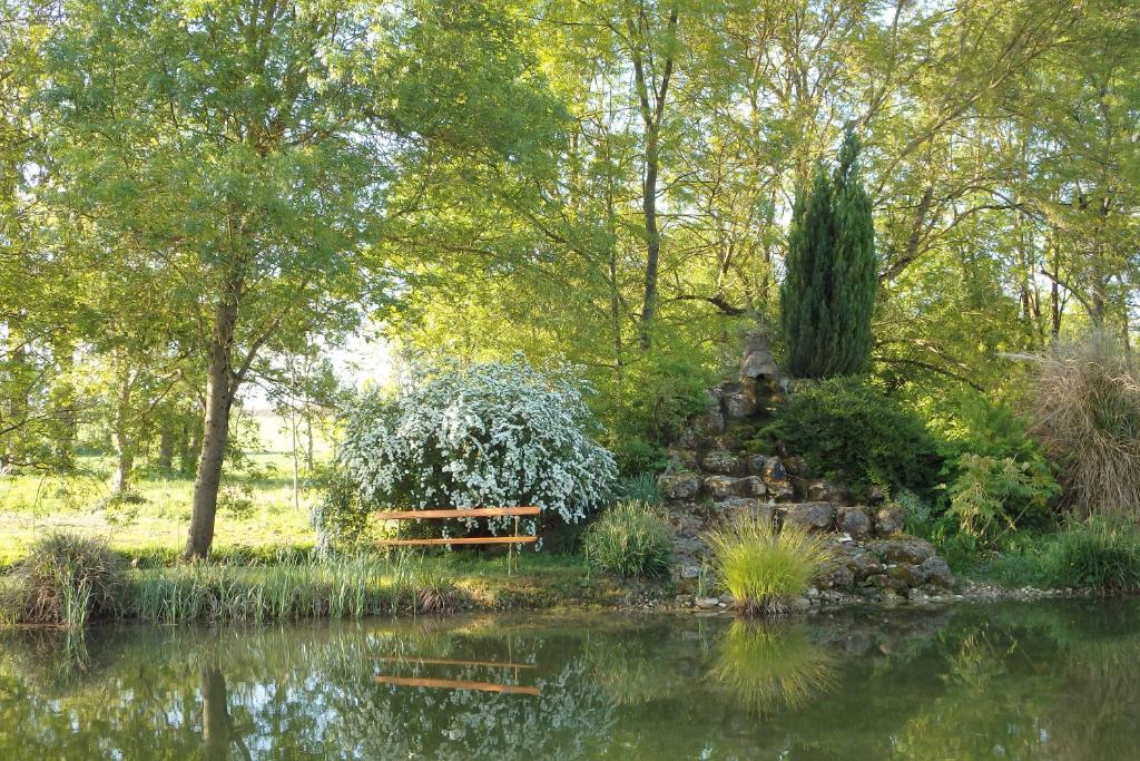 un banco sentado junto a un estanque en un parque en Le p'tit nid de Gabriel en Les Touches-de-Périgny