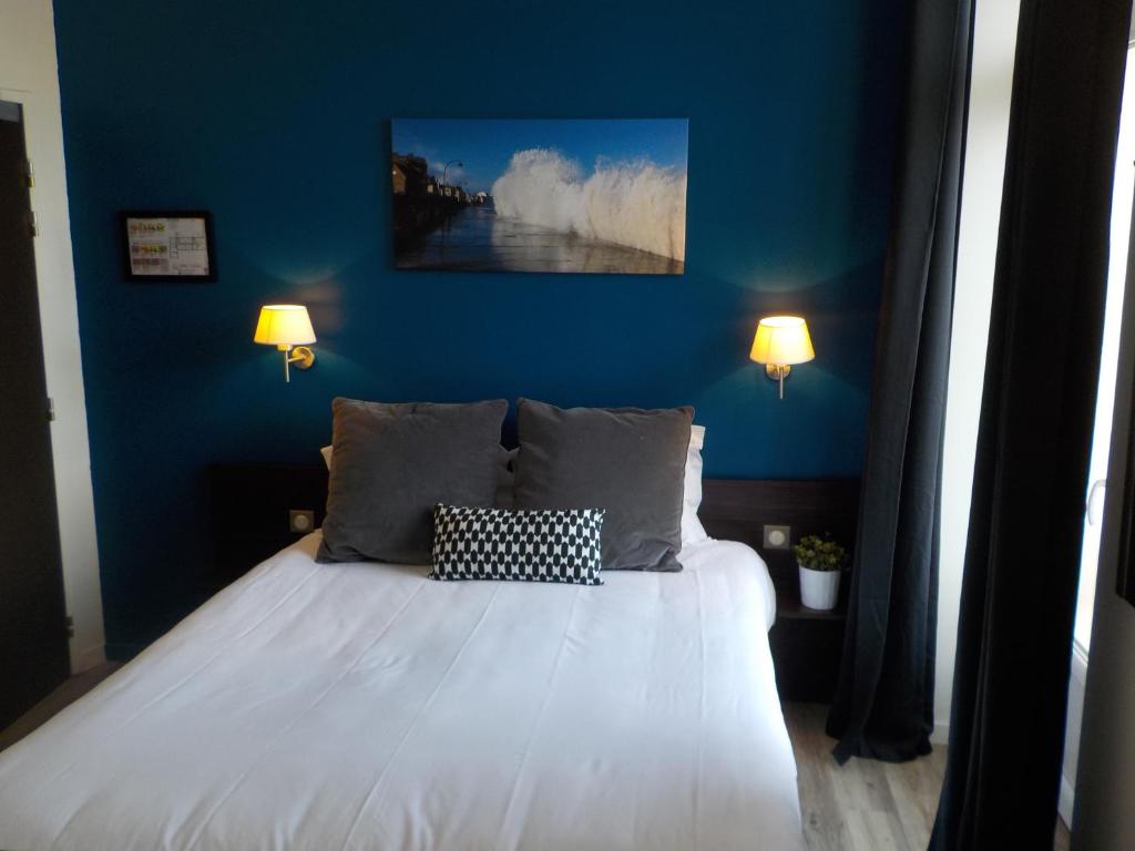 een slaapkamer met een bed met een blauwe muur bij Hôtel de Bretagne Dol centre ville in Dol-de-Bretagne