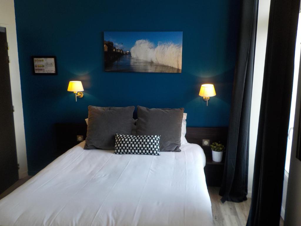 une chambre avec un lit avec un mur bleu dans l'établissement Hôtel de Bretagne Dol centre ville - Hotel et Restaurant, à Dol-de-Bretagne