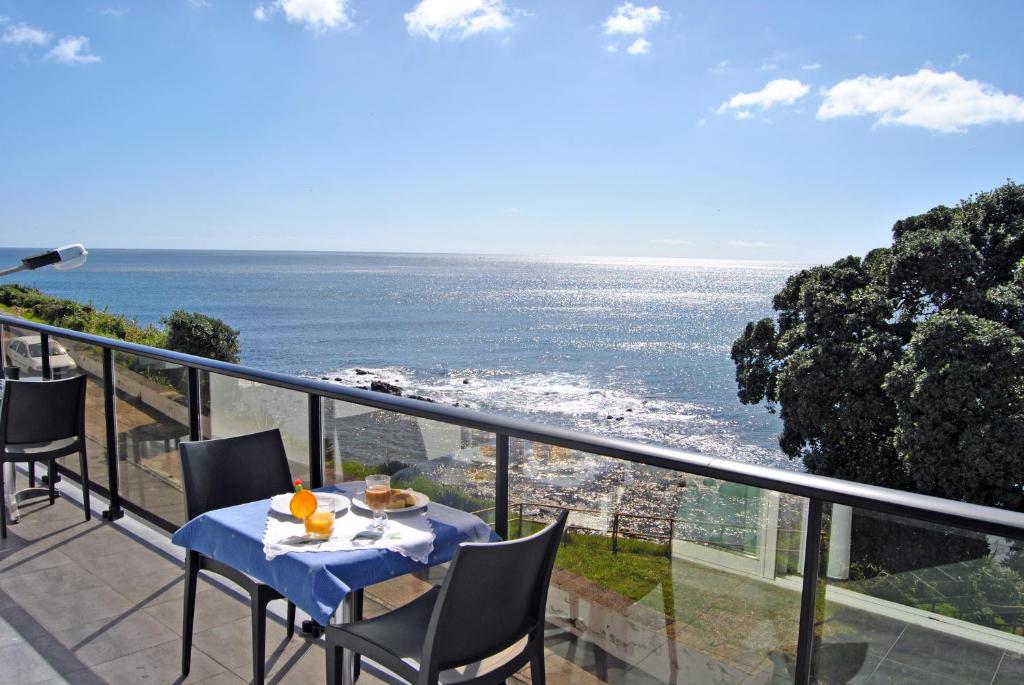 una mesa y sillas en un balcón con vistas al océano en Apartamentos 3 Praias en Ponta Delgada
