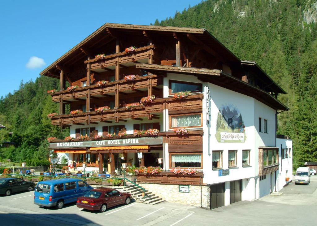 een groot gebouw met auto's geparkeerd voor het bij Hotel Alpina Regina in Biberwier