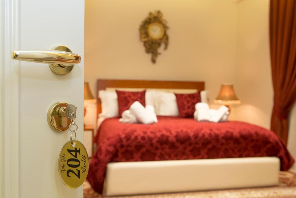 1 dormitorio con 1 cama con colcha roja en Vila Tako - Hotel, en Tirana