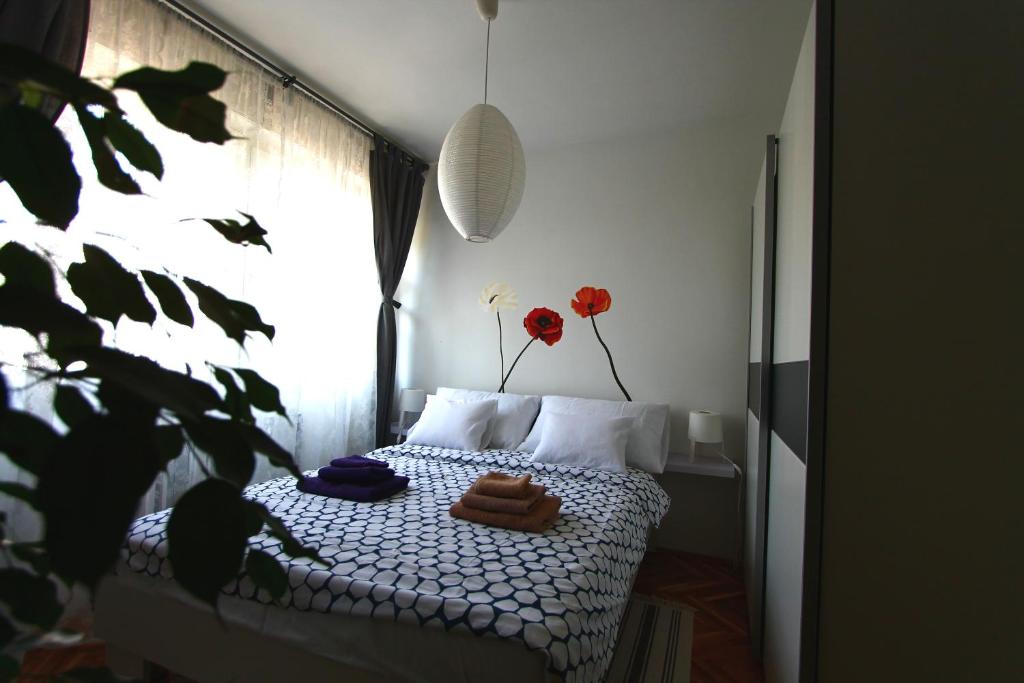 a bedroom with a bed and a window with red flowers at Apartment Melon in Zagreb