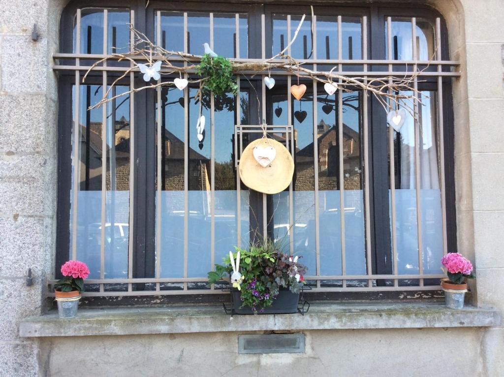 Una ventana con un sombrero y flores. en Kosy Suite en Saint-Aubin-du-Cormier