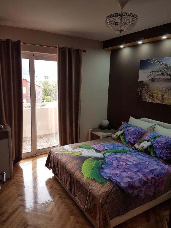 a bedroom with a bed with purple flowers on it at Apartments Vila Galileo in Budva