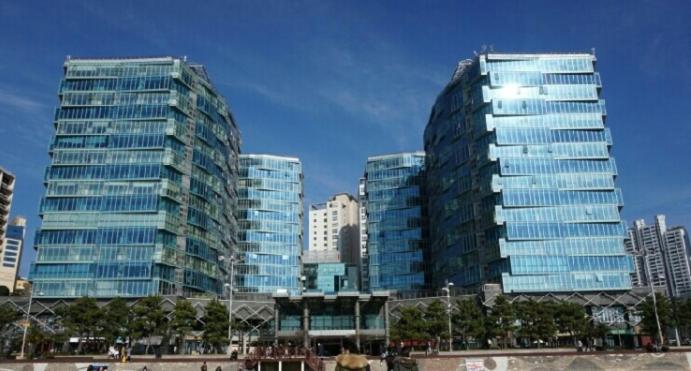 two tall glass buildings in a city at Haeundae Bada Condo in Busan