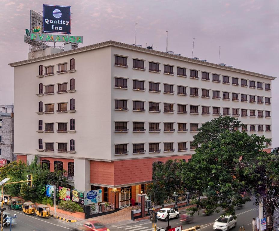 a large white building on a city street with traffic at Quality Hotel D V Manor in Vijayawāda