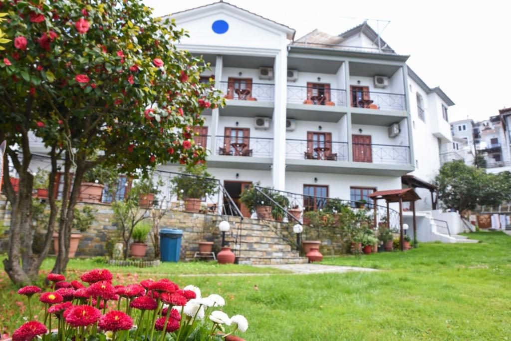 Biały budynek z czerwonymi kwiatami przed nim w obiekcie Hotel Eleana w mieście Agios Ioannis Pelio
