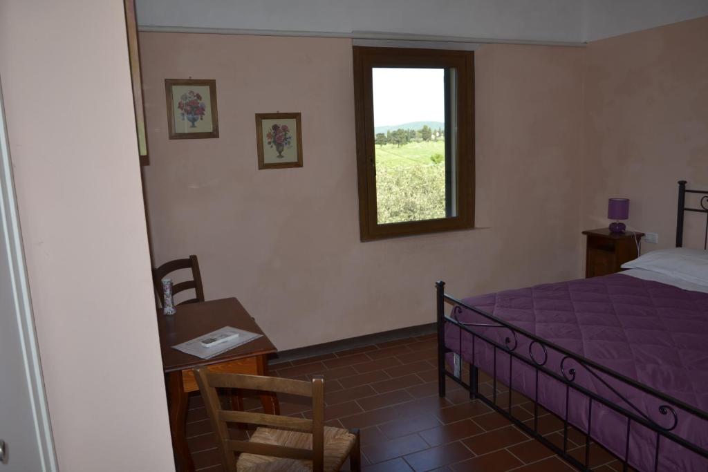 sypialnia z fioletowym łóżkiem i oknem w obiekcie Podere S.Giulia - casale Banditelle w mieście Venturina Terme