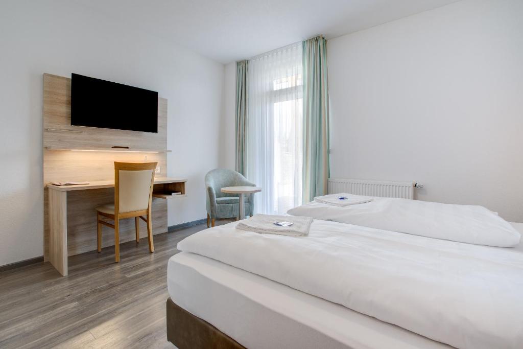 ein Hotelzimmer mit einem Bett, einem Schreibtisch und einem TV in der Unterkunft Landhotel Küffner in Pfedelbach