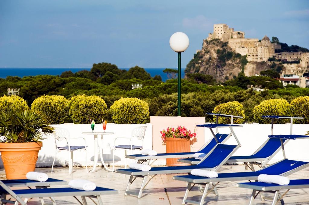 um pátio com cadeiras, uma mesa e um castelo em Hotel Bellevue Benessere & Relax em Ischia