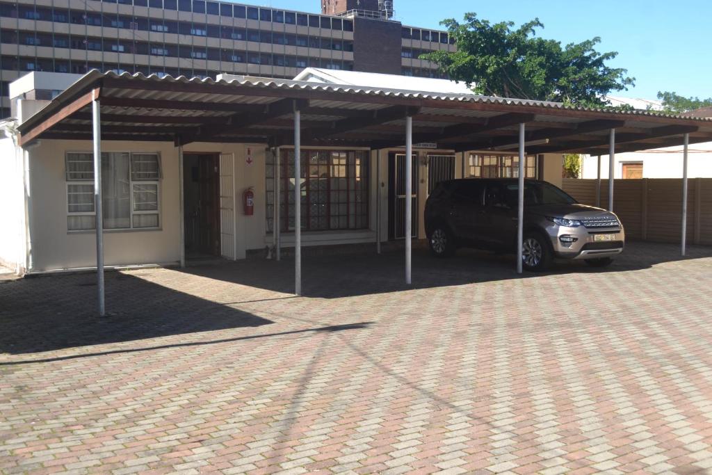un'auto parcheggiata sotto un padiglione accanto a un edificio di oasis guest house a East London