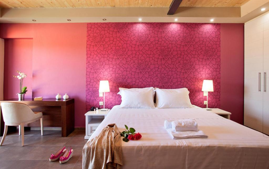 a bedroom with a pink wall with a bed and a desk at Ornella Beach Resort & Villas in Syvota
