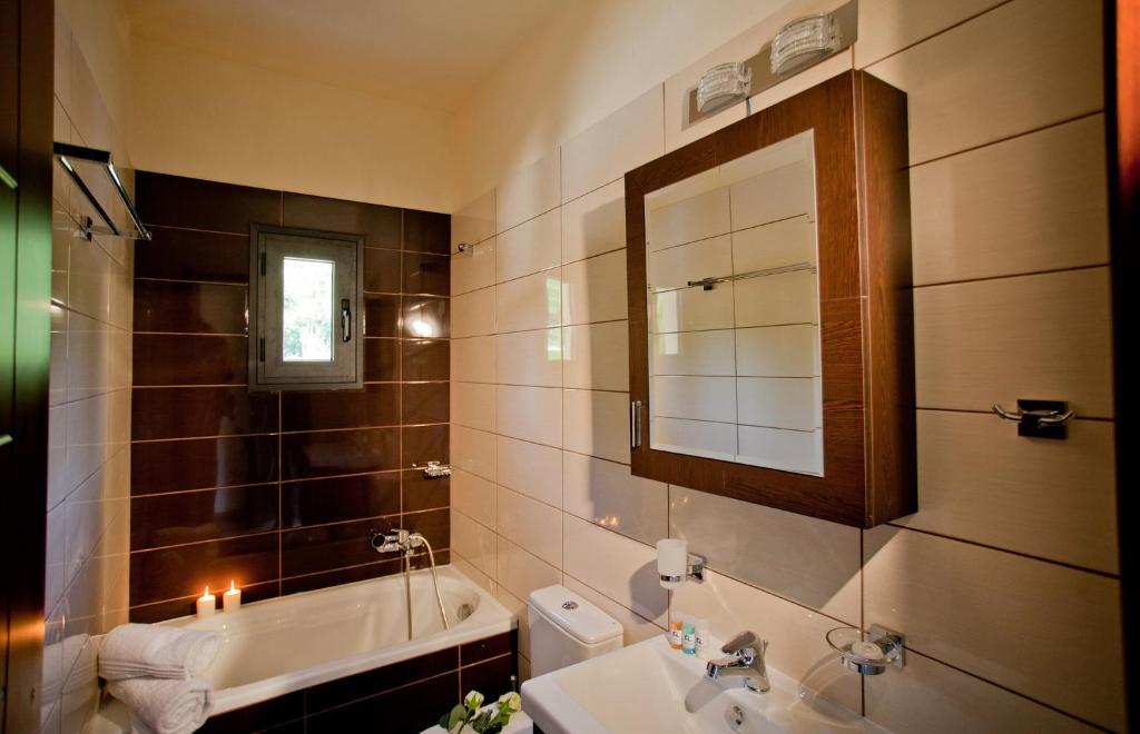 a bathroom with a sink and a toilet and a mirror at Ornella Beach Resort & Villas in Syvota