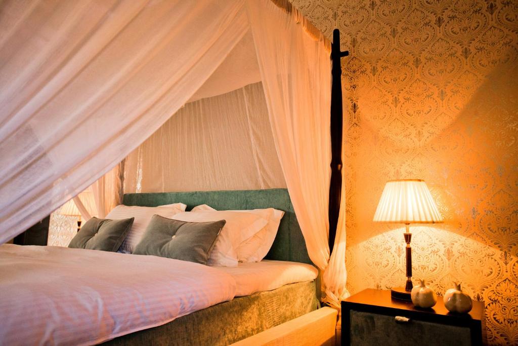 a bedroom with a bed with a canopy and a lamp at Ornella Beach Resort & Villas in Syvota