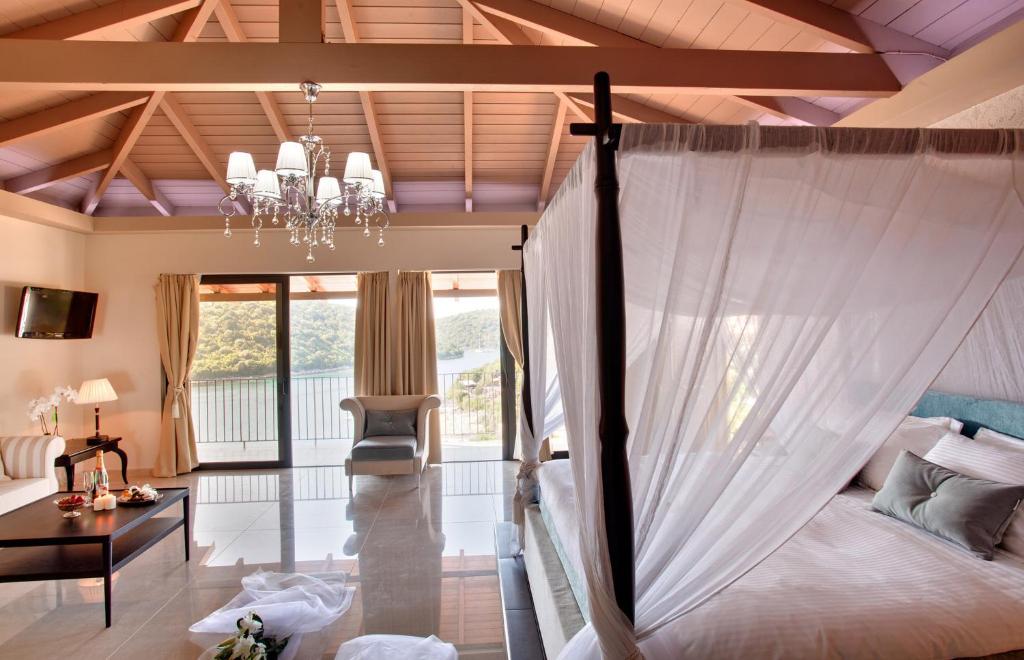 a bedroom with a canopy bed with a chandelier at Ornella Beach Resort & Villas in Syvota
