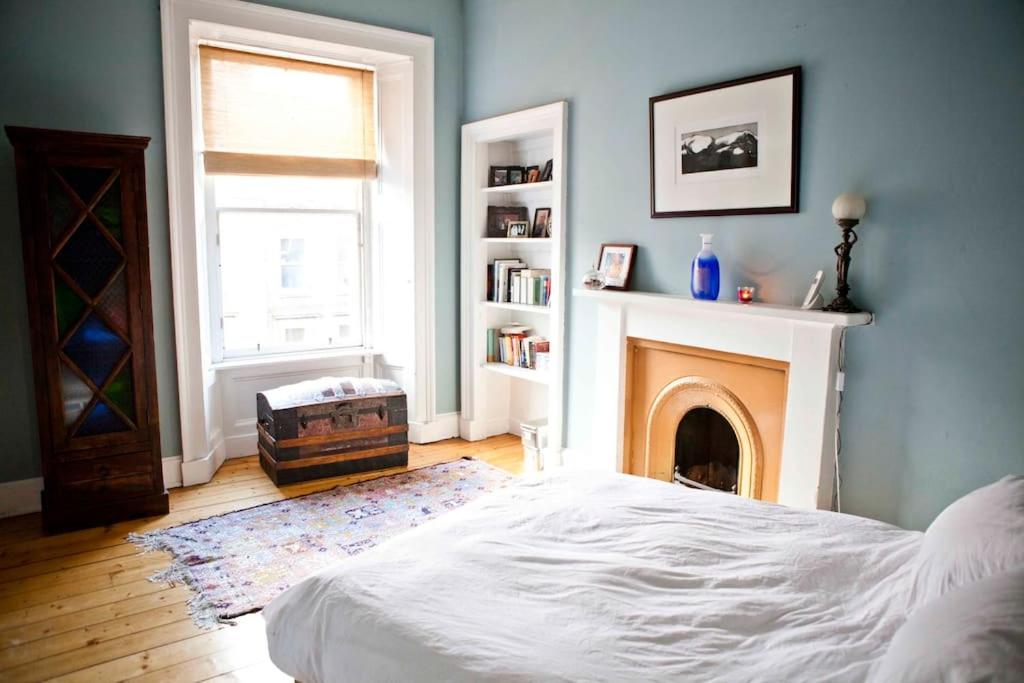 1 dormitorio con cama blanca y chimenea en Epicurean Clerk Apartment, en Edimburgo