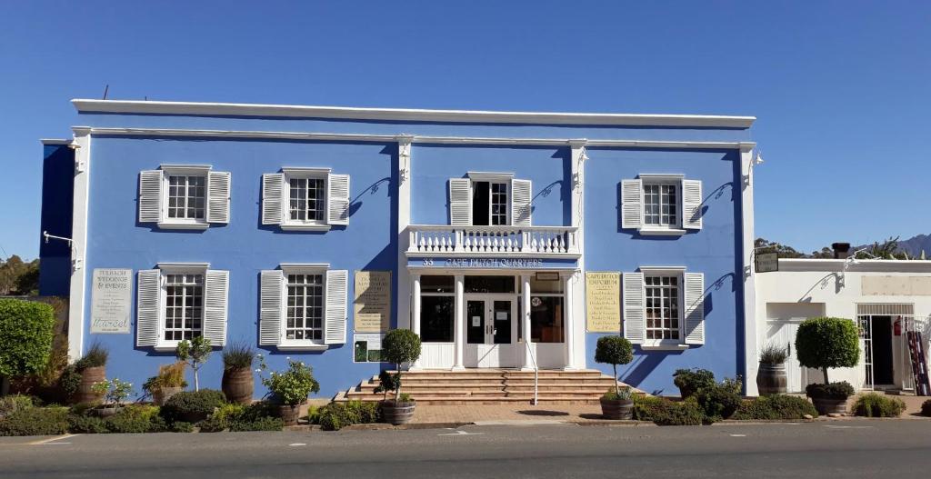 タルバにあるTulbagh Travelers Lodge - Cape Dutch Quartersの白いシャッターとポーチのある青い家