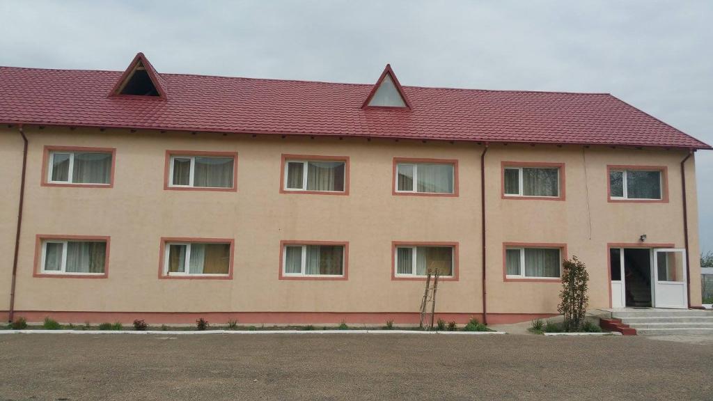 a large tan building with a red roof at Casa Rustica Apart & Rooms in Cîmpineanca