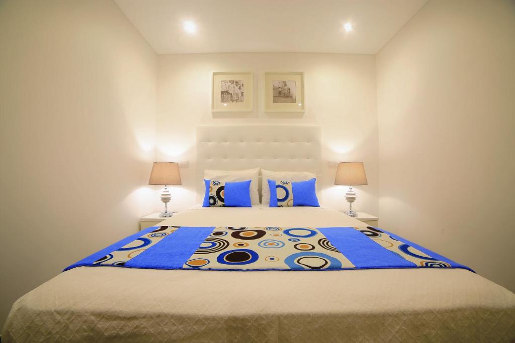 a bedroom with a large bed with blue pillows at Gaivota Holidays in Nazar&eacute;