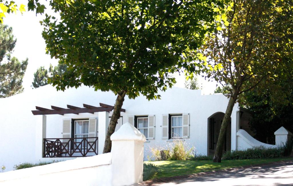 a white house with a tree in front of it at Zevenwacht Cottages in Kuilsrivier