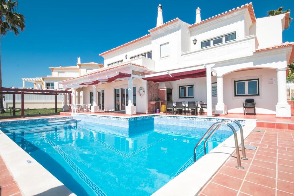 a villa with a swimming pool in front of a house at Pedro Mar in Albufeira