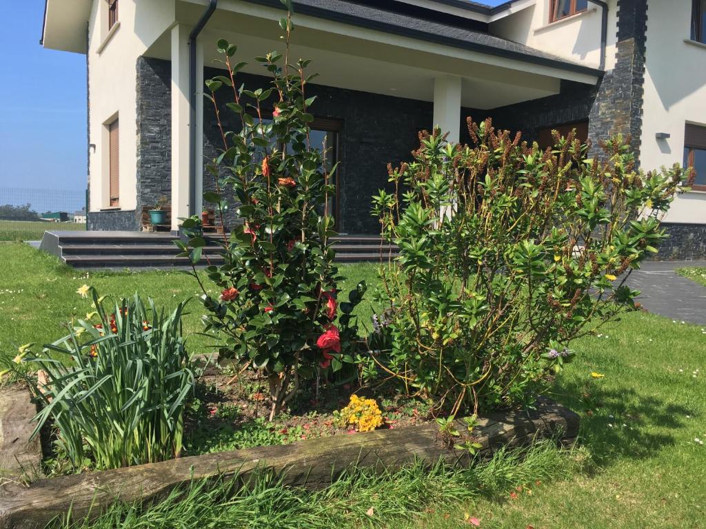 un jardín frente a una casa con flores en Chalet La Caleya en Otur