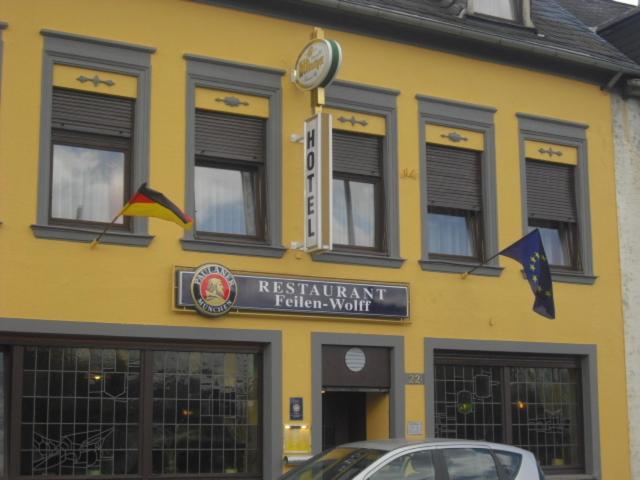 un bâtiment jaune avec une horloge à l'avant dans l'établissement Hotel Feilen-Wolff, à Trèves